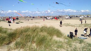 A beach with people flying kites and a sandy landscape with grass in the foreground. - Holiday house on Rømø with view over the Wadden Sea, free internet (Römö)