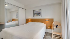 A hotel room with a large bed, a wooden headboard, a bedside table, a chair, a small shelf, and a painting on the wall. - Holiday house on Rømø with view over the Wadden Sea, free internet (Römö)