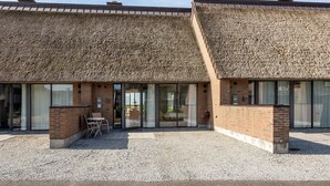 A building with a thatched roof, brick walls, and large sliding glass doors. - Holiday house on Rømø with view over the Wadden Sea, free internet (Römö)