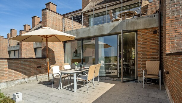 A patio with a table and chairs, a large umbrella, and a glass door leading to an interior space. - Holiday house on Rømø with view over the Wadden Sea, free internet (Römö)
