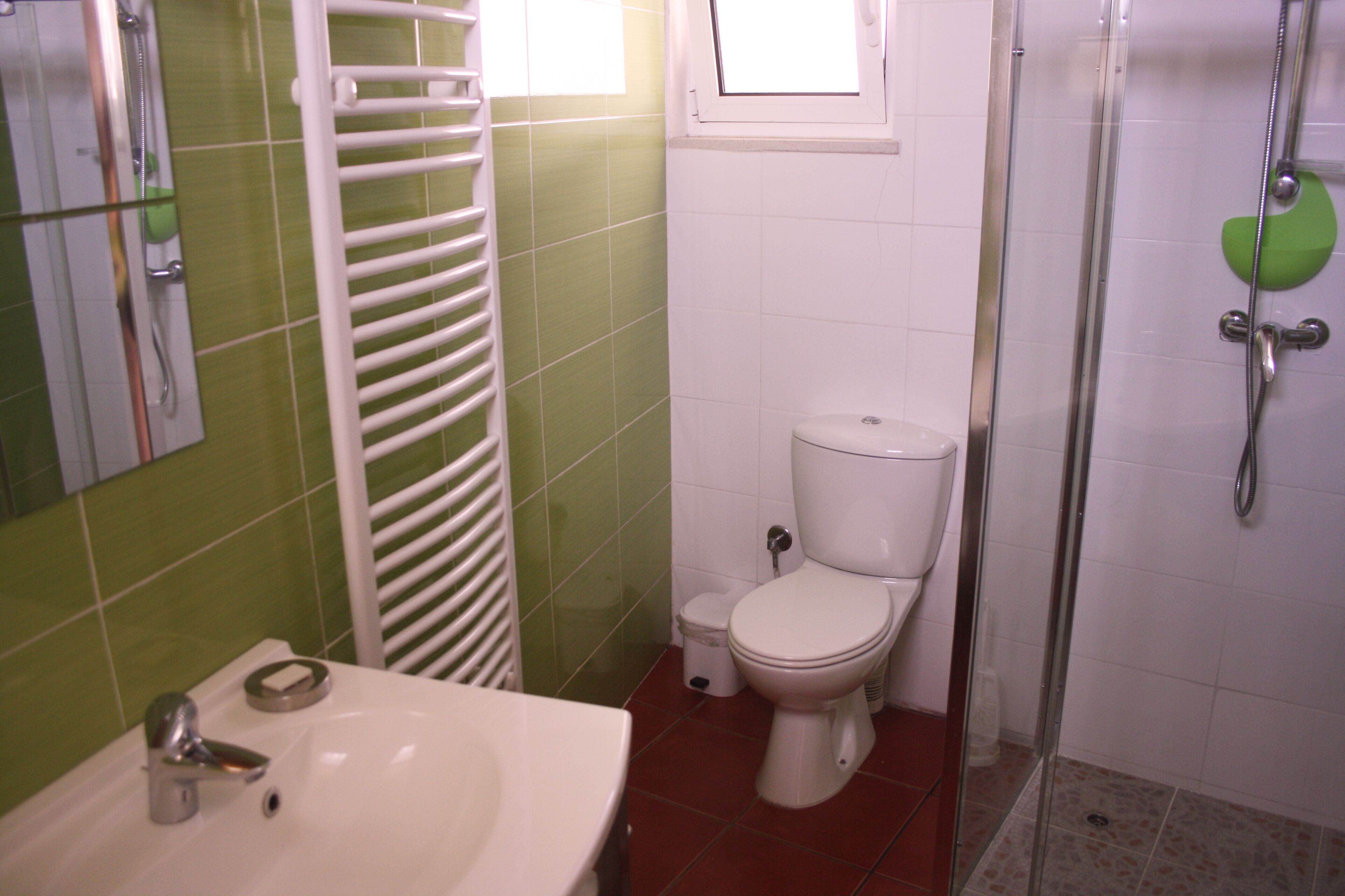 Een badkamer met een witte wastafel, toilet en douche.