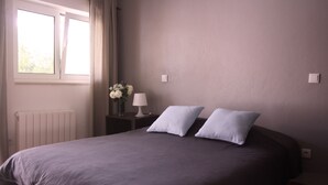 Une chambre à coucher avec un grand lit, une table de chevet avec une lampe et une fenêtre avec des rideaux.