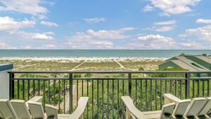 Ein Balkon mit Stühlen, der Blick auf Strand und Meer bietet.