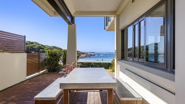 Un balcón con vista al mar, una mesa y una valla de madera.
