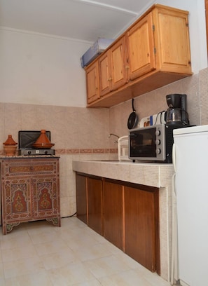 Compact kitchen with microwave, coffee maker, and cabinet with decorative patterns.