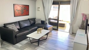 Ein modernes Wohnzimmer mit einem schwarzen Ledersofa, einem weißen Couchtisch und einer kleinen Elefantfigur.