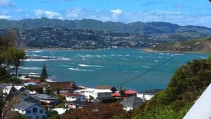 A coastal town with houses near the water, mountains in the background, and a clear sky.