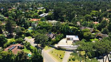 An aerial view of a residential area with houses, trees, and a modern building with a flat roof.