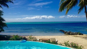 A clear blue pool with a view of the ocean and beach.