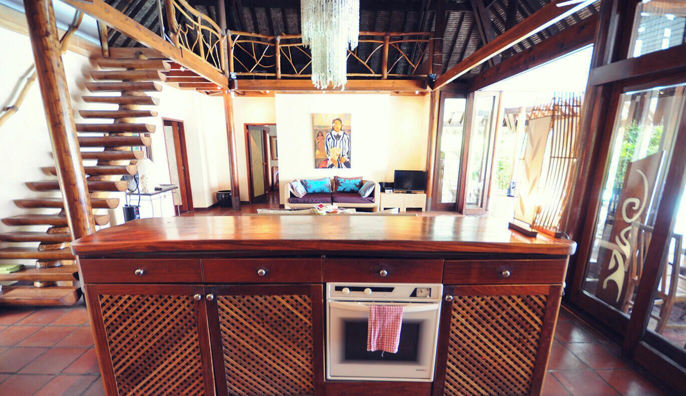 A spacious kitchen with a central island, a built-in oven, and a dining area with a sofa and television.
