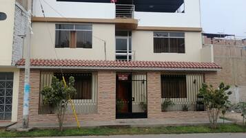Un edificio de dos pisos con techo de tejas, un balcón en el nivel superior y un cartel que indica una agencia de viajes.