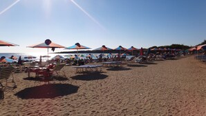 A beach with rows of umbrellas and sun loungers, a sandy shore, and the sea in the background. - Luxury 5* apartment overlooking 2 swimming pools.  (Peyia)