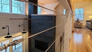 Un salon moderne doté d’une cheminée, de planchers en bois et de grandes fenêtres.