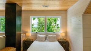 Une chambre avec une grande fenêtre, un plafond en bois et un lit avec deux oreillers.