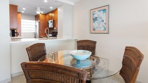 A dining area with a glass table, wicker chairs, a microwave, and a coffee maker.