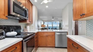 A modern kitchen with wooden cabinets, stainless steel appliances, and a view to the outside.