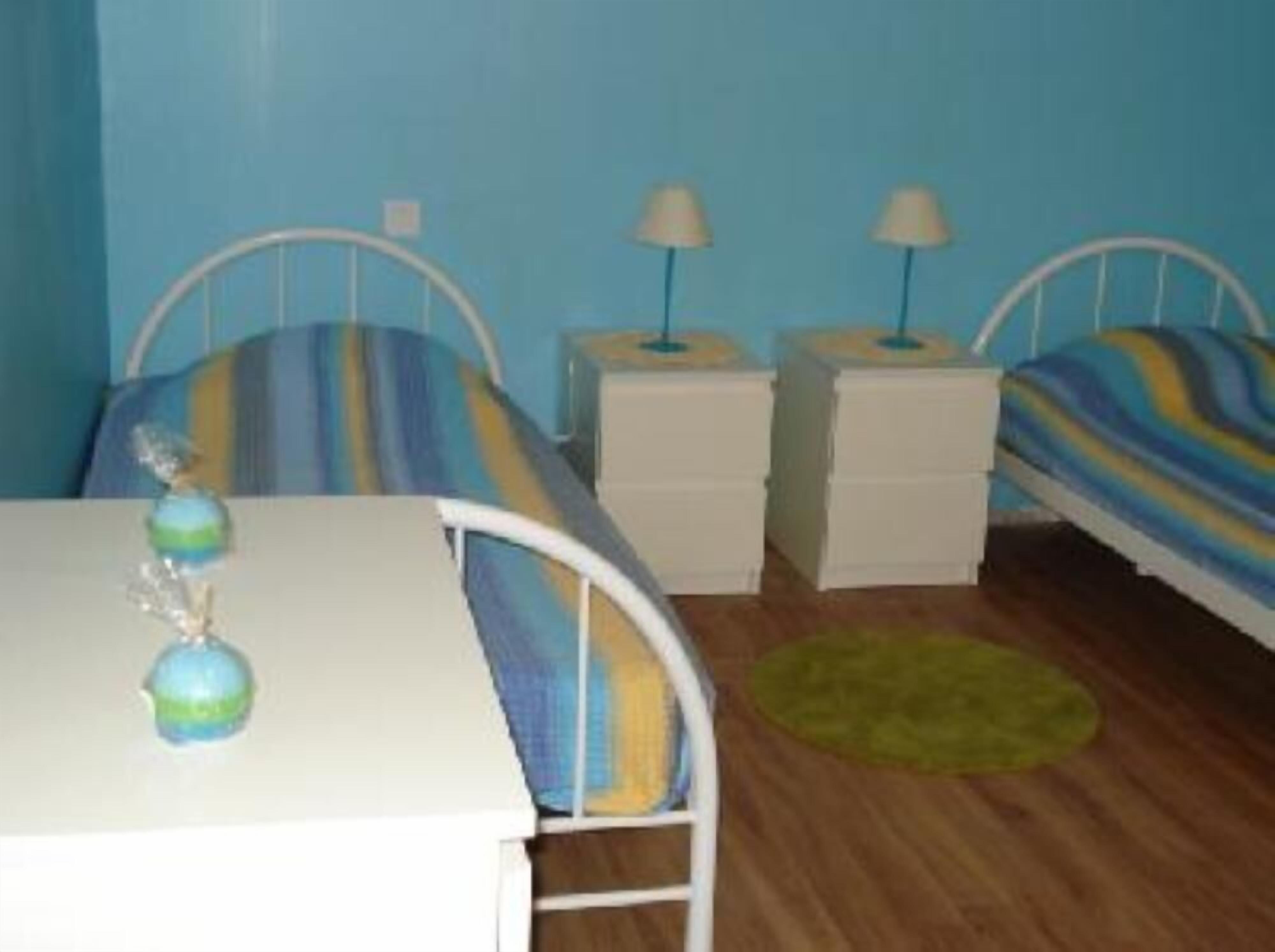 A room with two beds, a table, and a lamp.
