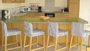Una cocina con armarios de madera, microondas, cafetera y una isla grande con taburetes de bar a rayas.