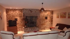 Una sala de estar con una pared de piedra, una chimenea y un conjunto de sofás.