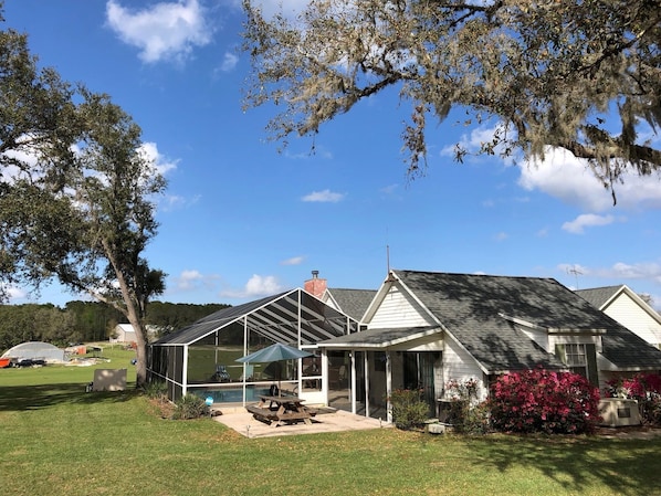 A house with a covered patio, a swimming pool, and a lawn. - Fly-in place to stay close to The Villages (Fruitland Park)