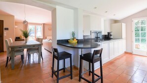A modern kitchen with a central island, bar stools, and a dining table with chairs. - Valbonne Quiet villa with magnesium pool (Valbonne)