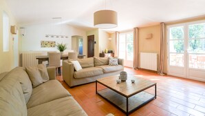 A spacious living room with a large sofa, a coffee table, and a dining area with chairs and a table. - Valbonne Quiet villa with magnesium pool (Valbonne)