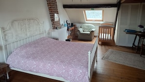Un dormitorio con cama, una silla, una cuna, un escritorio y una ventana.