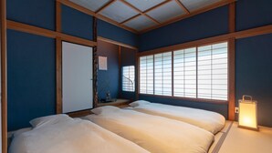 A traditional Japanese-style room with tatami flooring, a shoji screen window, and a futon bed. - Hinaya Higashiyama (Kanazawa)