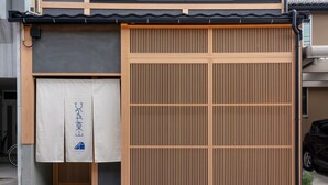 A traditional Japanese building with a sliding wooden door, a small entrance, and a bicycle parked outside. - Hinaya Higashiyama (Kanazawa)