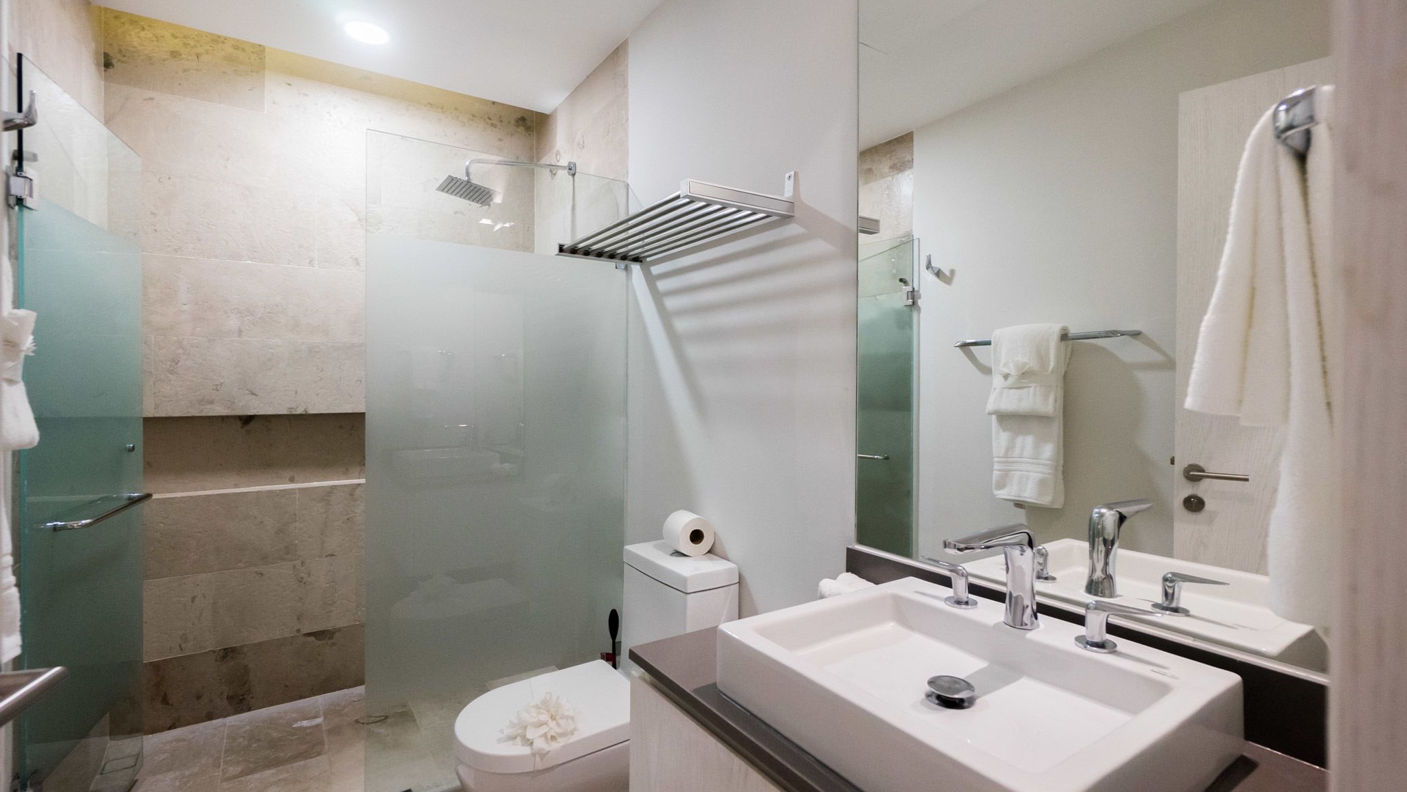 A modern bathroom with a glass-enclosed shower, a white sink, and a large mirror.