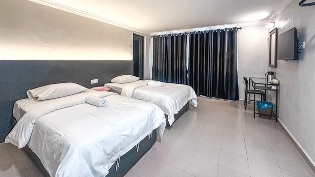 A hotel room with two single beds, a small desk with a chair, a TV, and a window with curtains. - Super OYO 473 Comfort Hotel 2 (Klang)