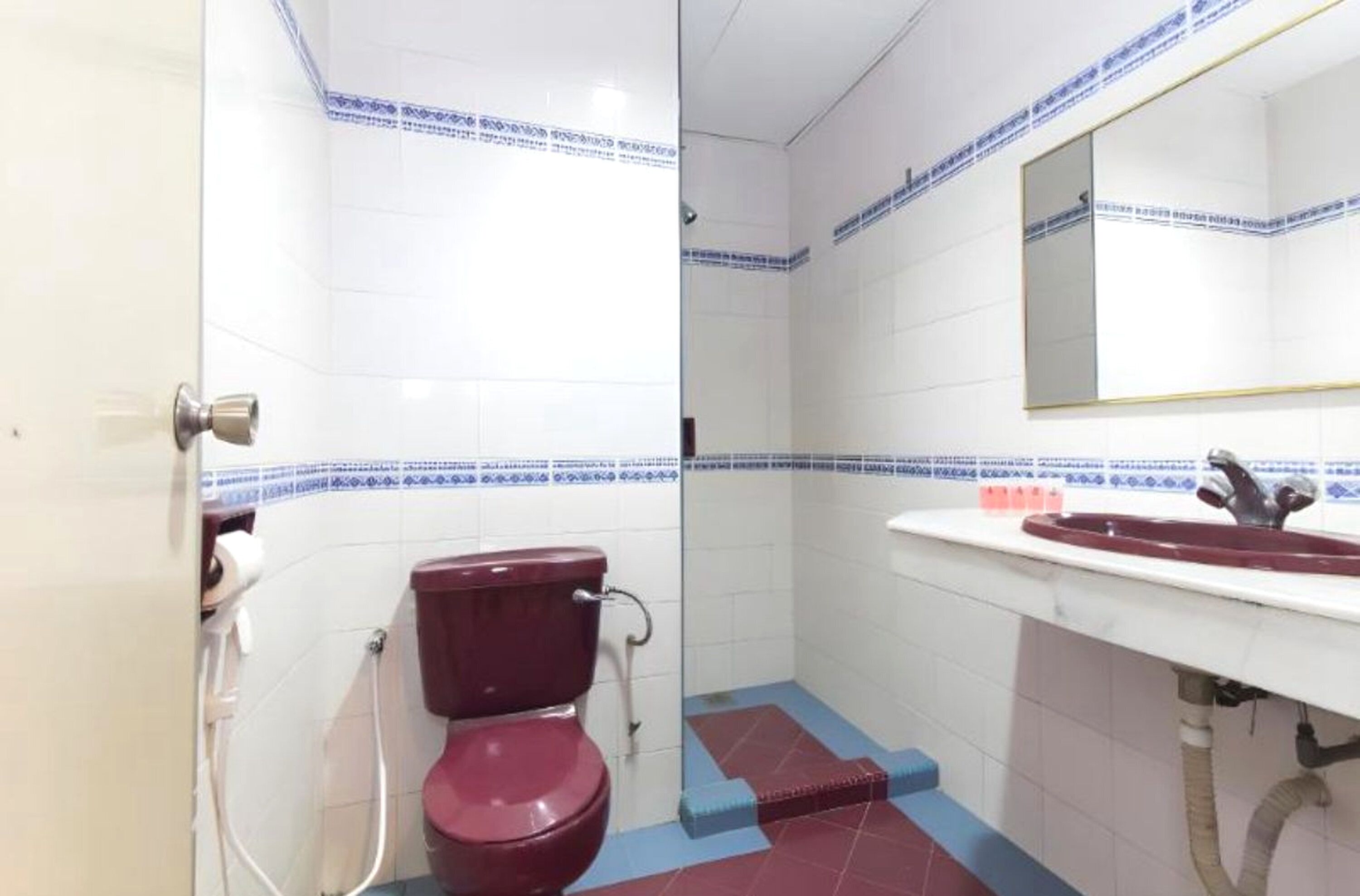 A bathroom with a toilet, sink, and mirror.