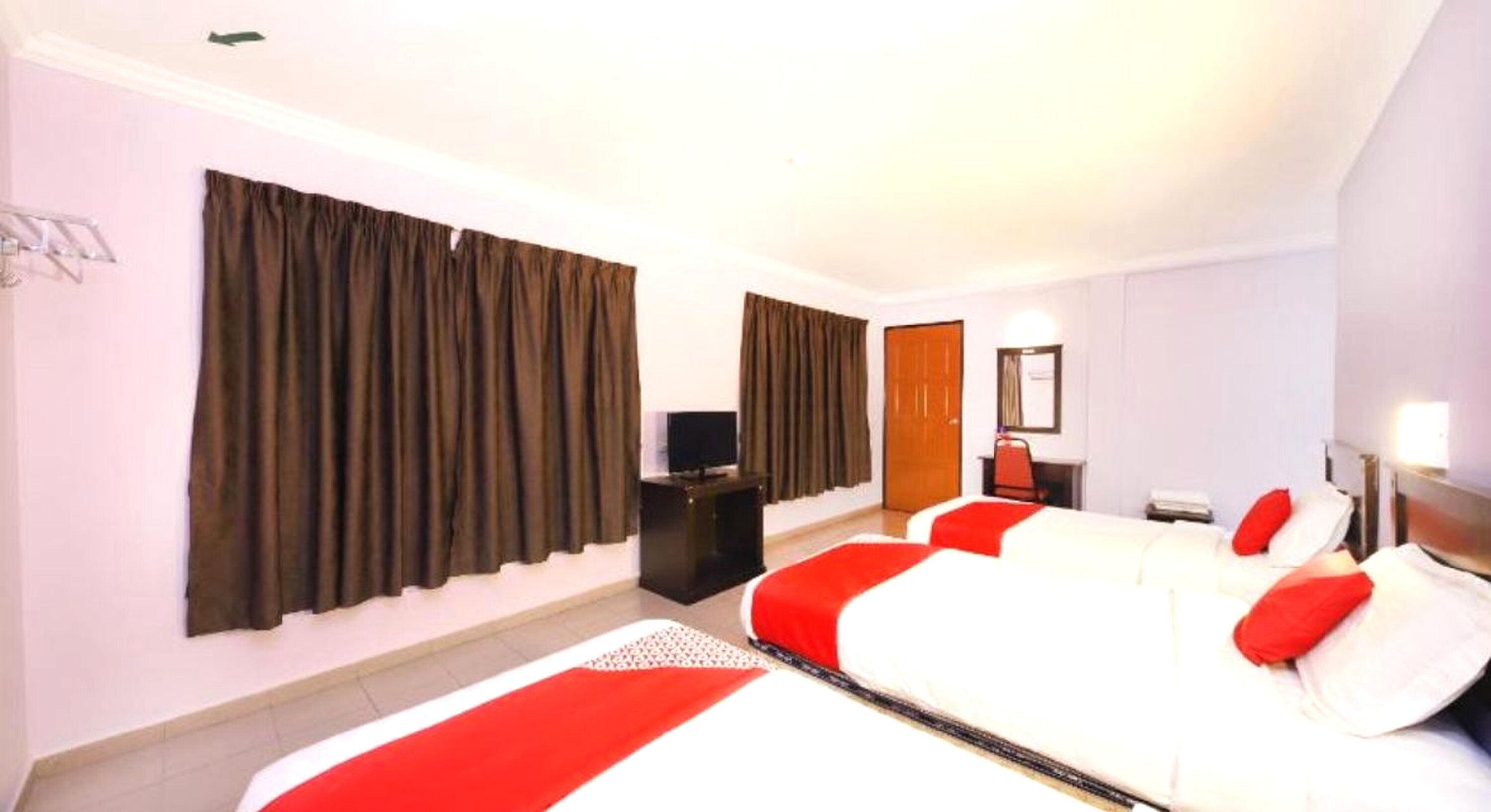 Una habitación de hotel con cama, cortinas, escritorio, televisión y espejo.