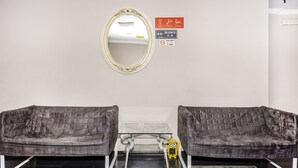 A room with two grey upholstered sofas, a small glass table, a mirror, and a yellow toy. - Super OYO 473 Comfort Hotel 2 (Klang)