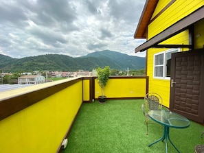 A yellow building with a balcony, a potted plant, and a glass table. - Puli Diary (Puli)