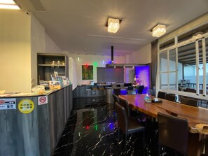 A modern restaurant with a marble floor, a wooden dining table, and a bar area with colorful lighting. - Puli Diary (Puli)