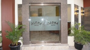 Ein Hotel Eingang mit Glastür und der Aufschrift 'ALOHA HOTEL'.