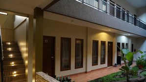 Eine Hotelhalle mit Treppe, einer Rezeption und einem kleinen Gartenbereich.