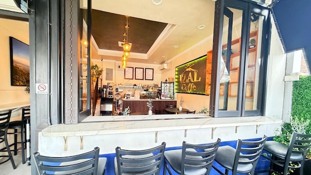 A bar area with a counter, black chairs, and a 'VAL Caffe' sign. - Hometel Suites - Los Angeles (Koreatown) (Los Angeles)
