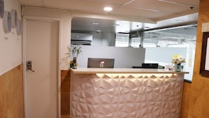A reception desk with a geometric pattern, a laptop, and a vase with flowers. - Hometel Suites - Los Angeles (Koreatown) (Los Angeles)