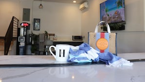 A hotel lobby with a white coffee mug, a striped towel, and a handbag on a counter. - Hometel Suites - Los Angeles (Koreatown) (Los Angeles)