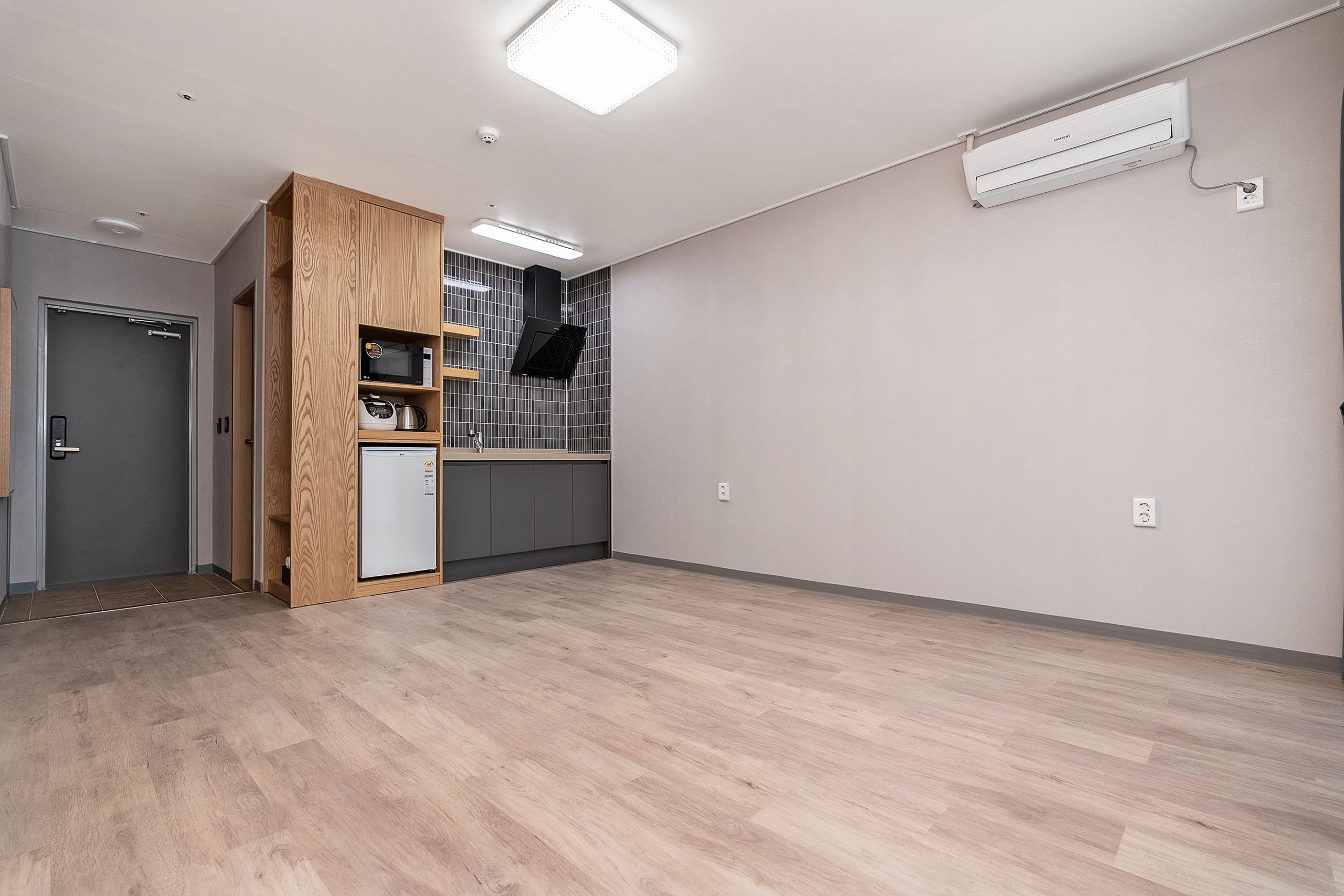 Un'ampia stanza con un'armadio in legno, un angolo cottura e un forno a microonde integrato.