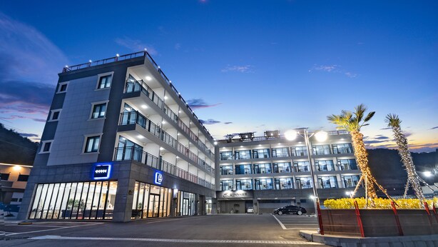 A multi-story hotel with a modern design, featuring a prominent entrance with glass doors and a sign. - Gold Beach Resort (Yeosu)