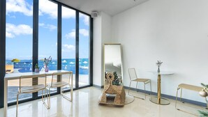 A modern room with a large window, a round table, a chair, a small rug, and a tall mirror. - Gold Beach Resort (Yeosu)