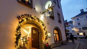 A hotel entrance with a stone archway, a sign above the door, and a satellite dish on the building. - Altstadt Hotel Wolf (Salzburg)