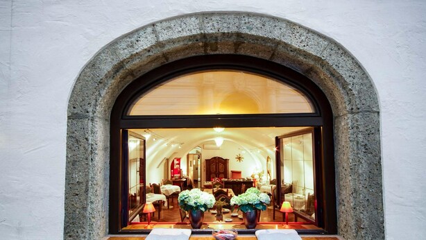 A hotel lobby with a stone archway, a reception desk, and potted plants. - Altstadt Hotel Wolf (Salzburg)