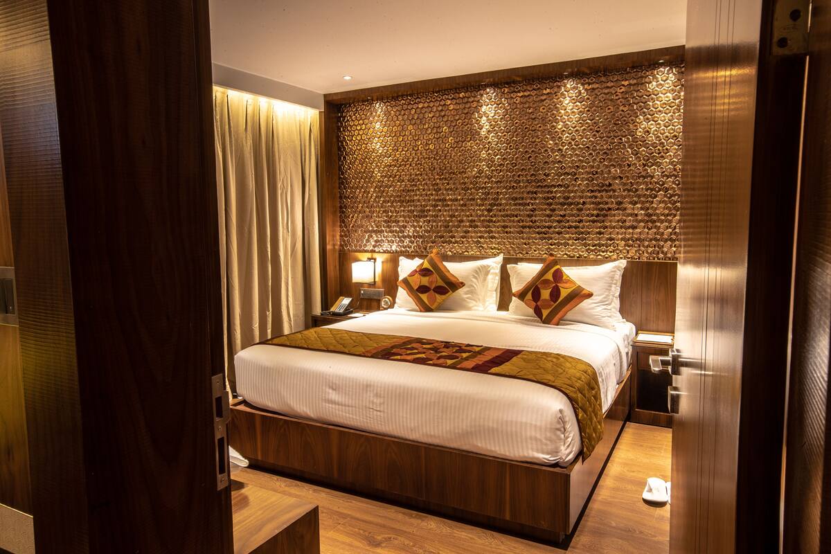A hotel room with a large bed, wooden headboard, and a textured wall.