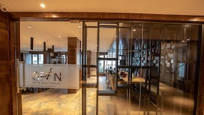 A modern interior with a glass door entrance, a visible dining area with tables and chairs, and a sign reading "SPAN INTERNATIONAL". - Hotel Span International (Kanayannur)