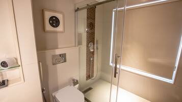 Een moderne badkamer met een douchecabine, toilet en een plankje met een haardroger.