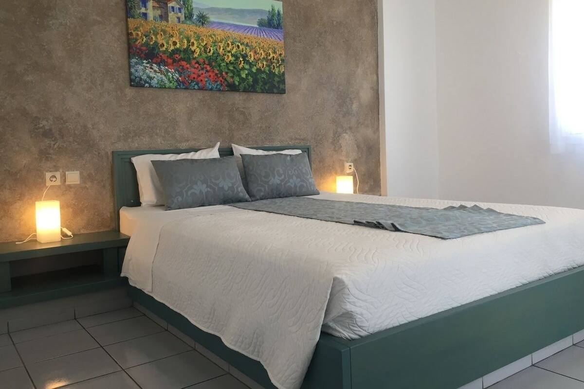A bedroom with a bed, a nightstand, a wall-mounted painting, and bedside lamps.